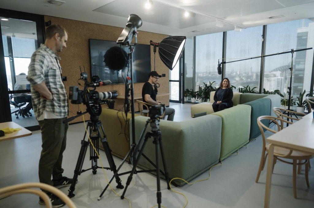 Man filming with camera and filming person on lounge.