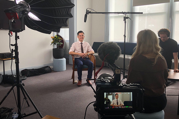 Man sitting for interview with camera and two production crew
