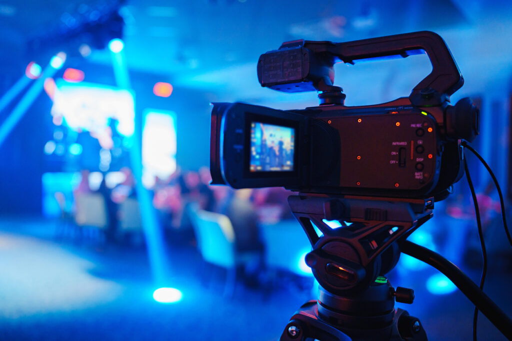 Videographer filming a live tech event with stage and audience in Australia